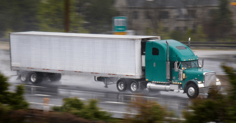 Freight truck travelling on rough and wet road